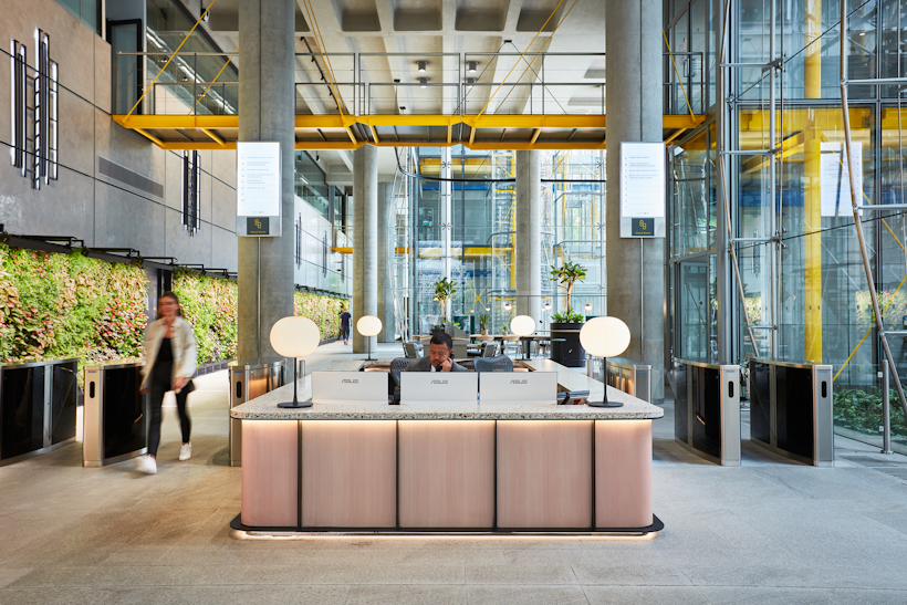 large open modern reception area in big office building with lit up green wall running the length