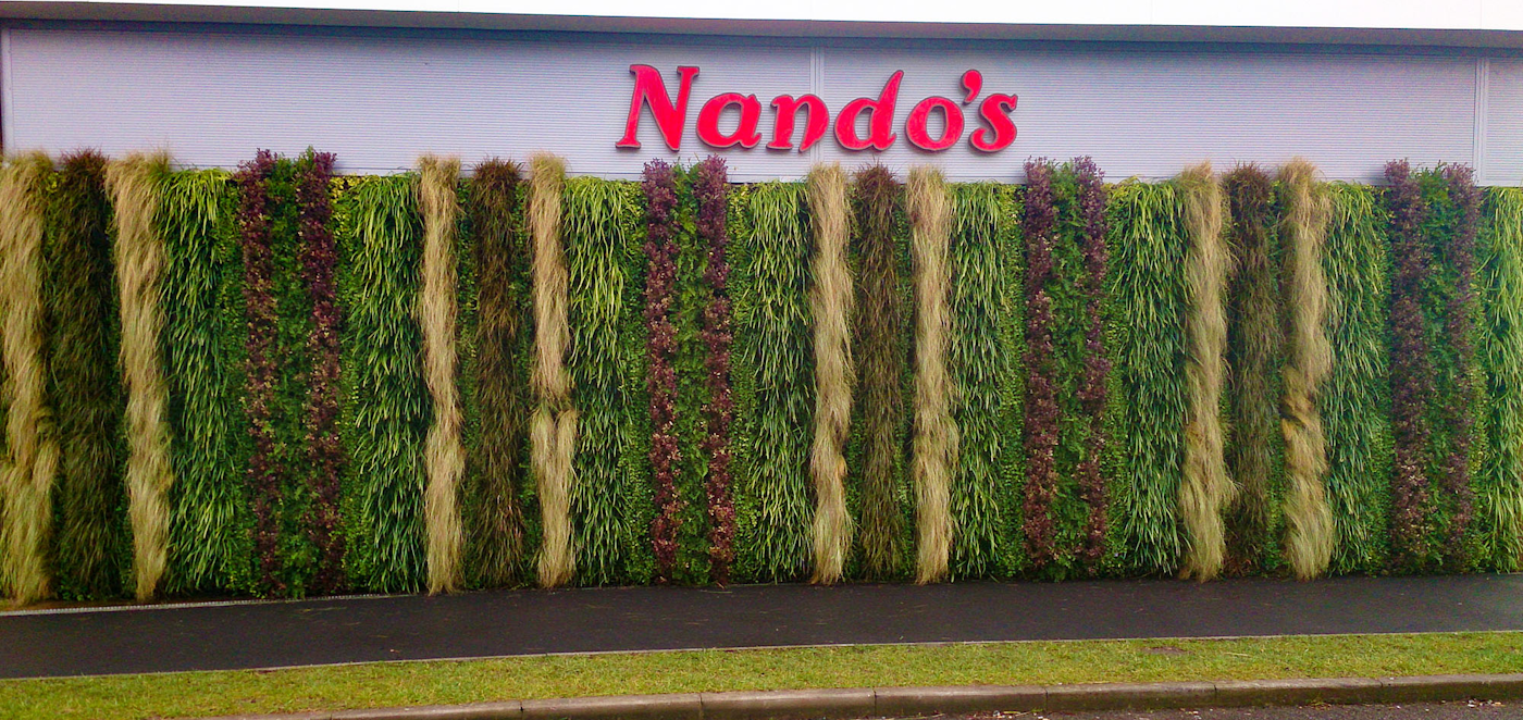 striped living wall at a retail park under Nando's sign