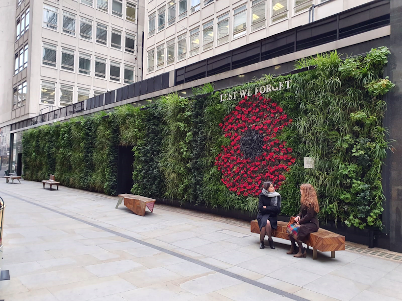 living wall with red flowers and people on a bench