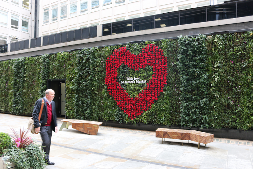 evergreen striped living wall along a pedestrianised street in a busy city with red heart in the wall with signage