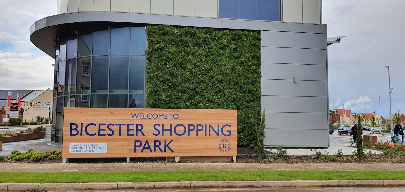 commercial facade with a wooden sign in front of a green wall