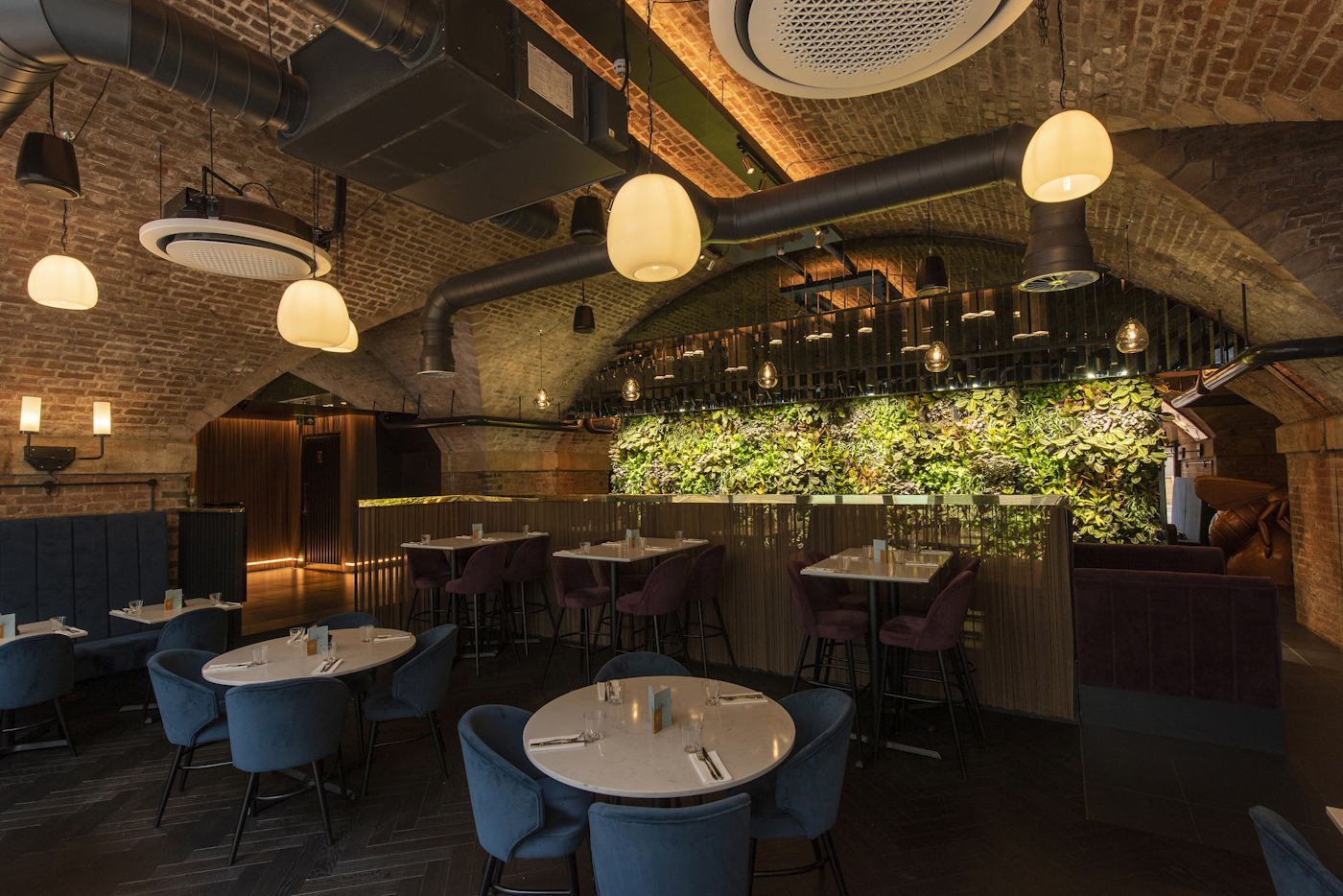 restaurant area with brick walls and lit up living wall in the background