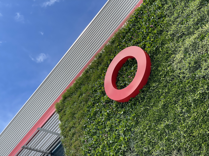 commercial building facade with red signage in an evergreen living wall