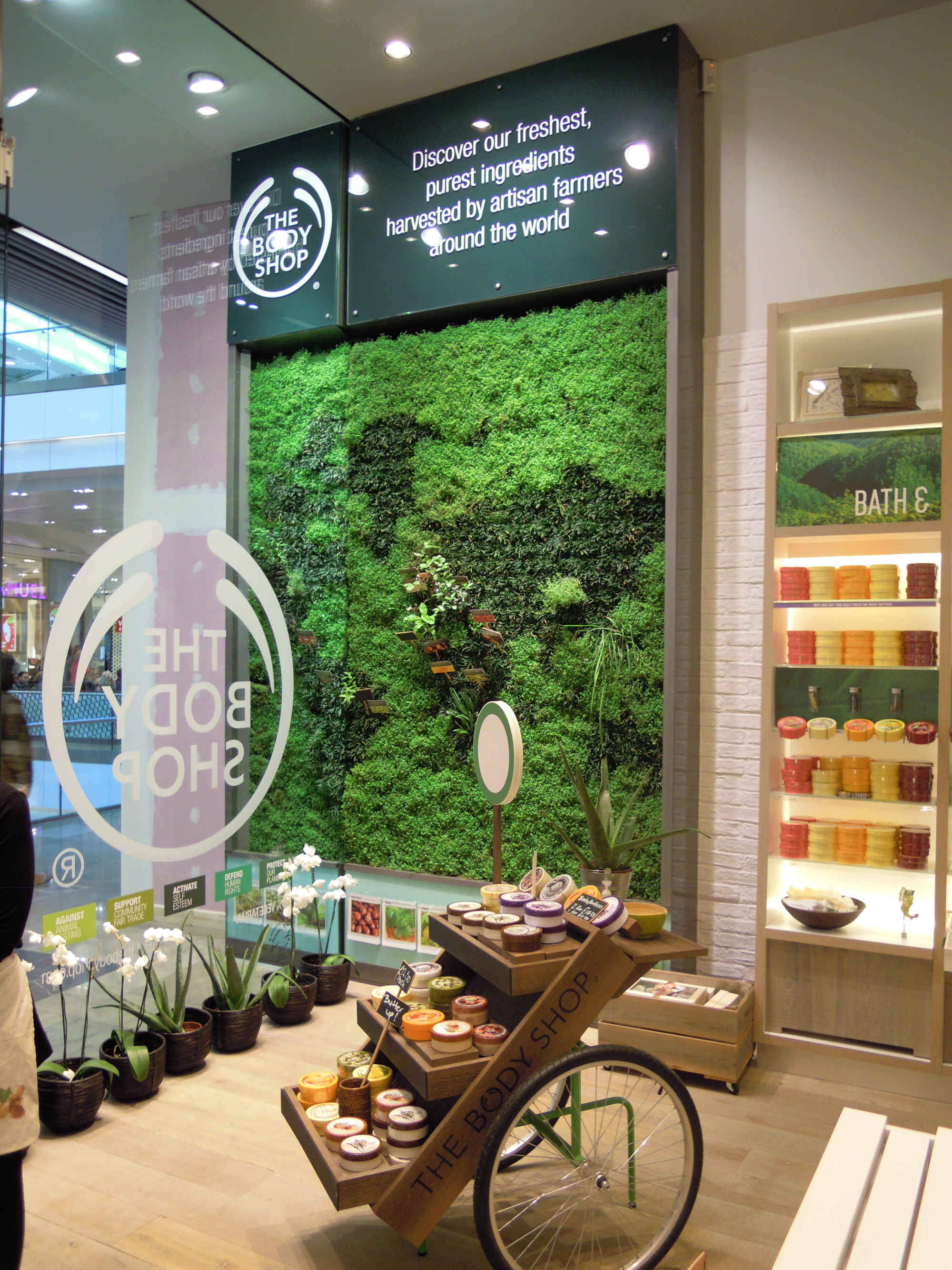 inside the body shop store in a shopping mall with soap products and a living wall