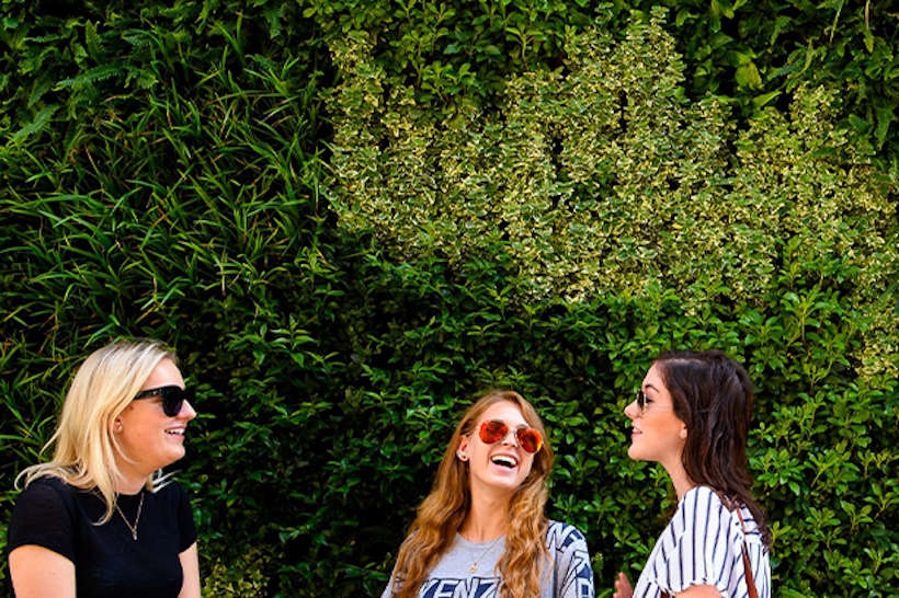 Women laughing with living wall backdrop